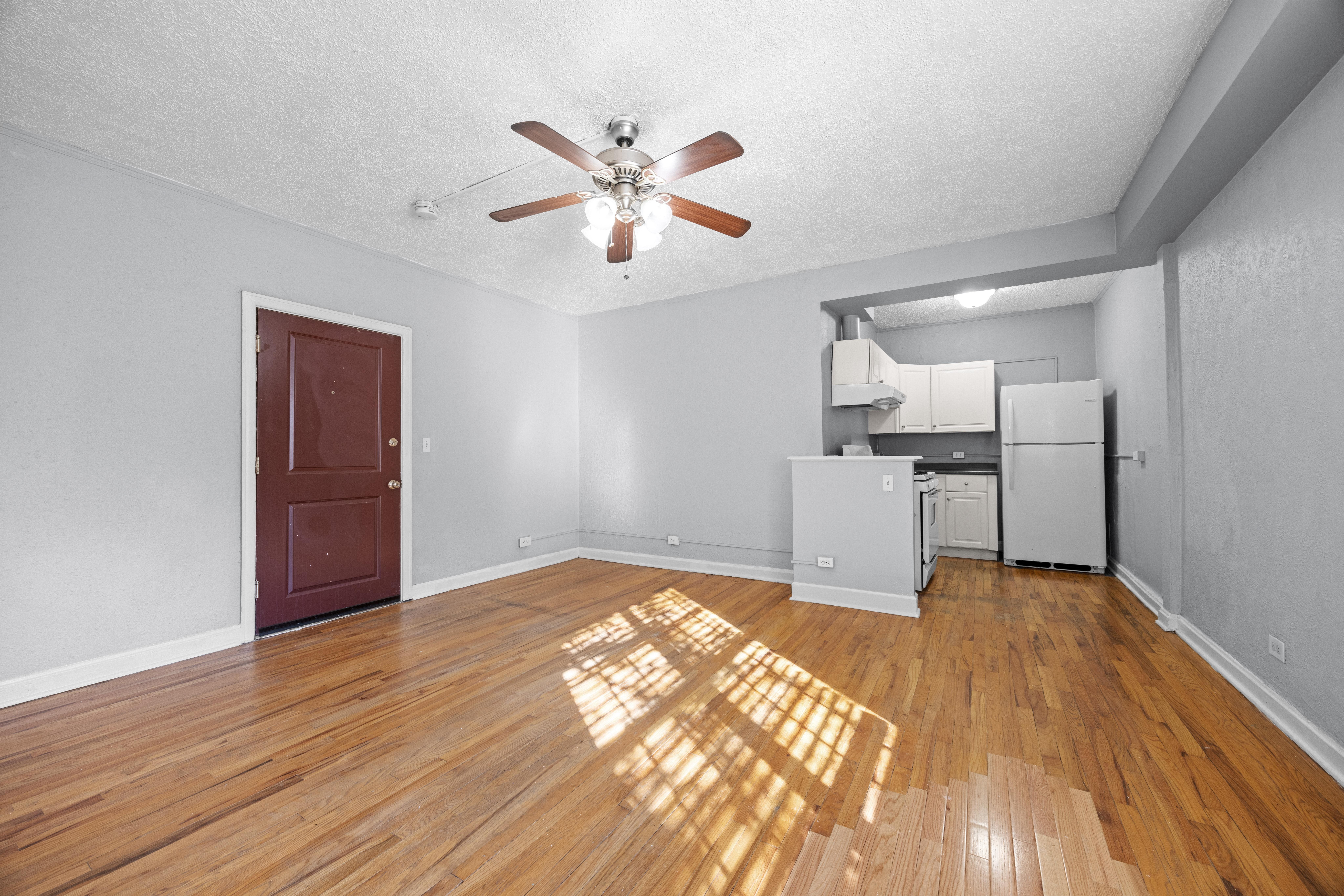 A room with a ceiling fan and wooden floors.